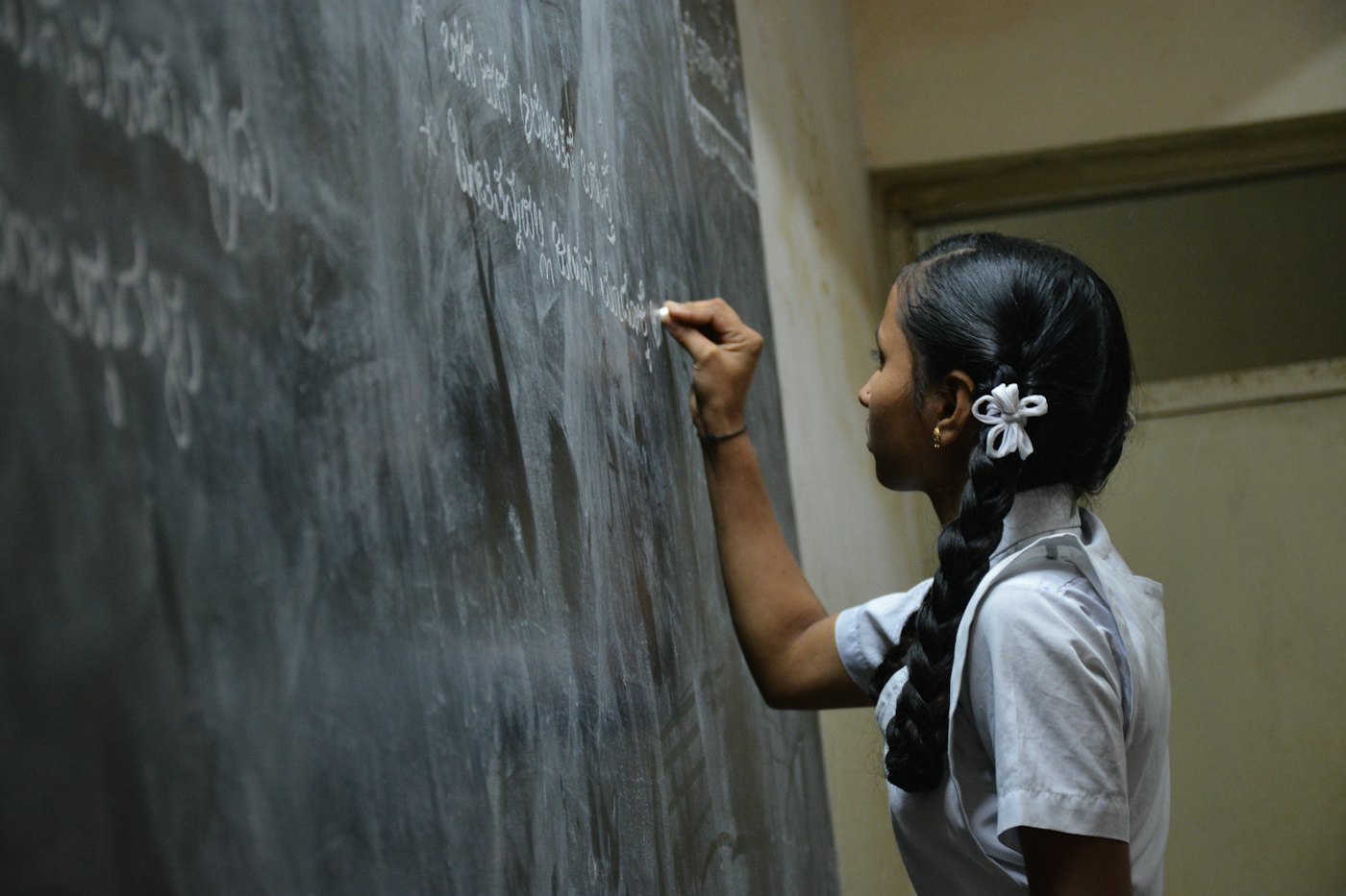 A schoolgirl writing on a chalkboard.