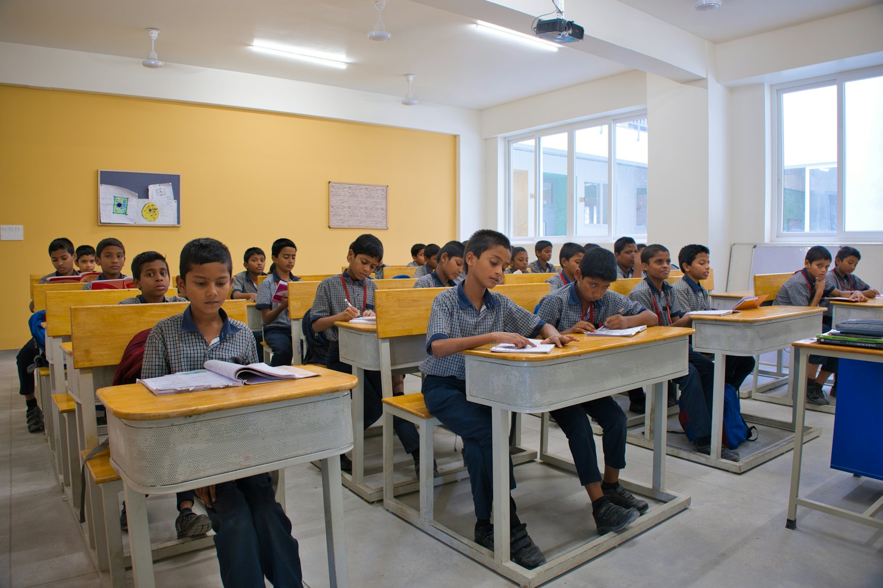 Students at their desks in a bright classroom, each marked by the AI camera as present.
