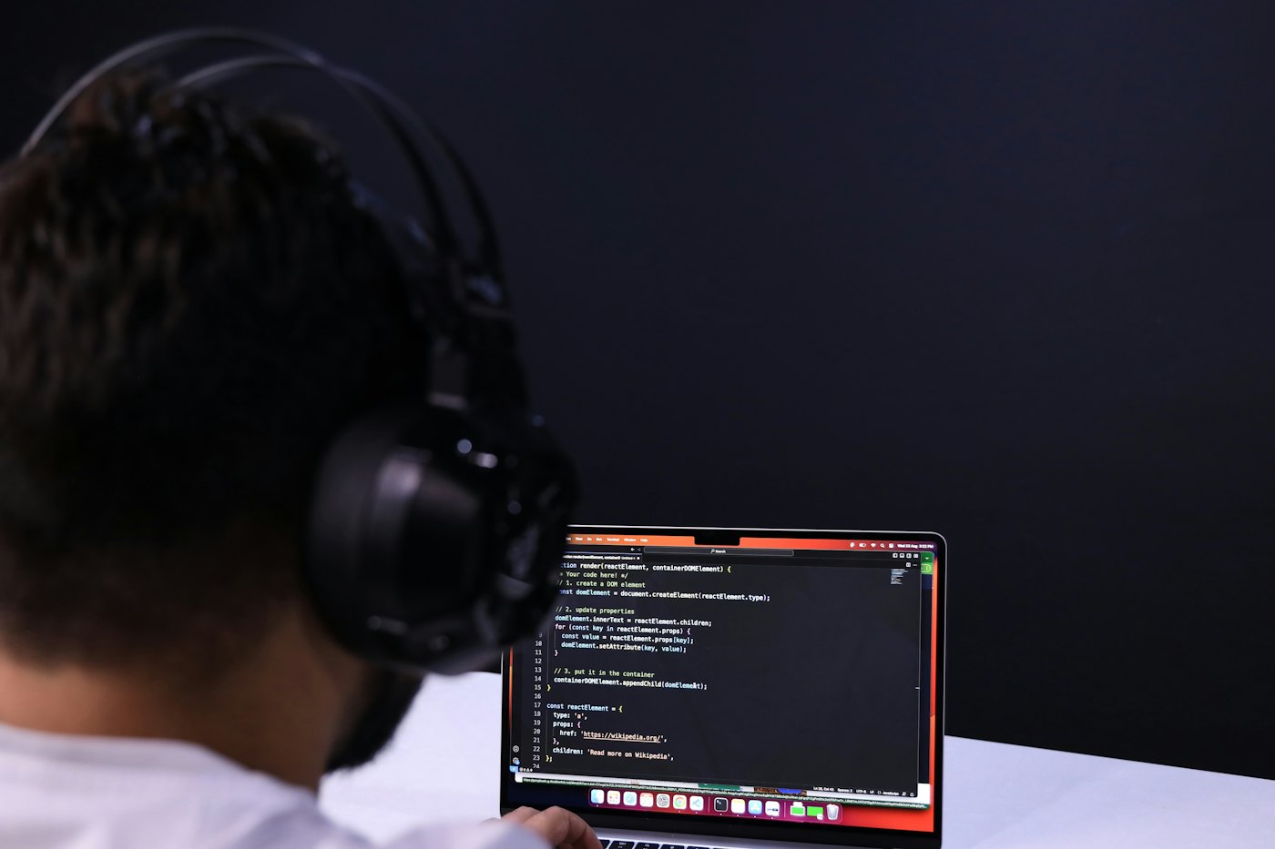 An engineer in headphones writing code on a laptop.