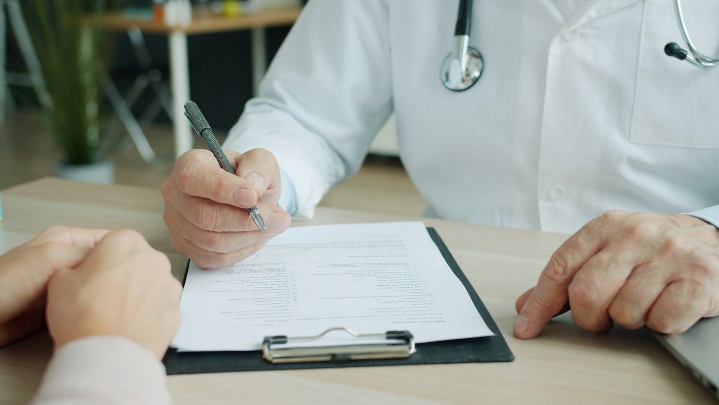 A doctor writing a prescription on a clipboard.