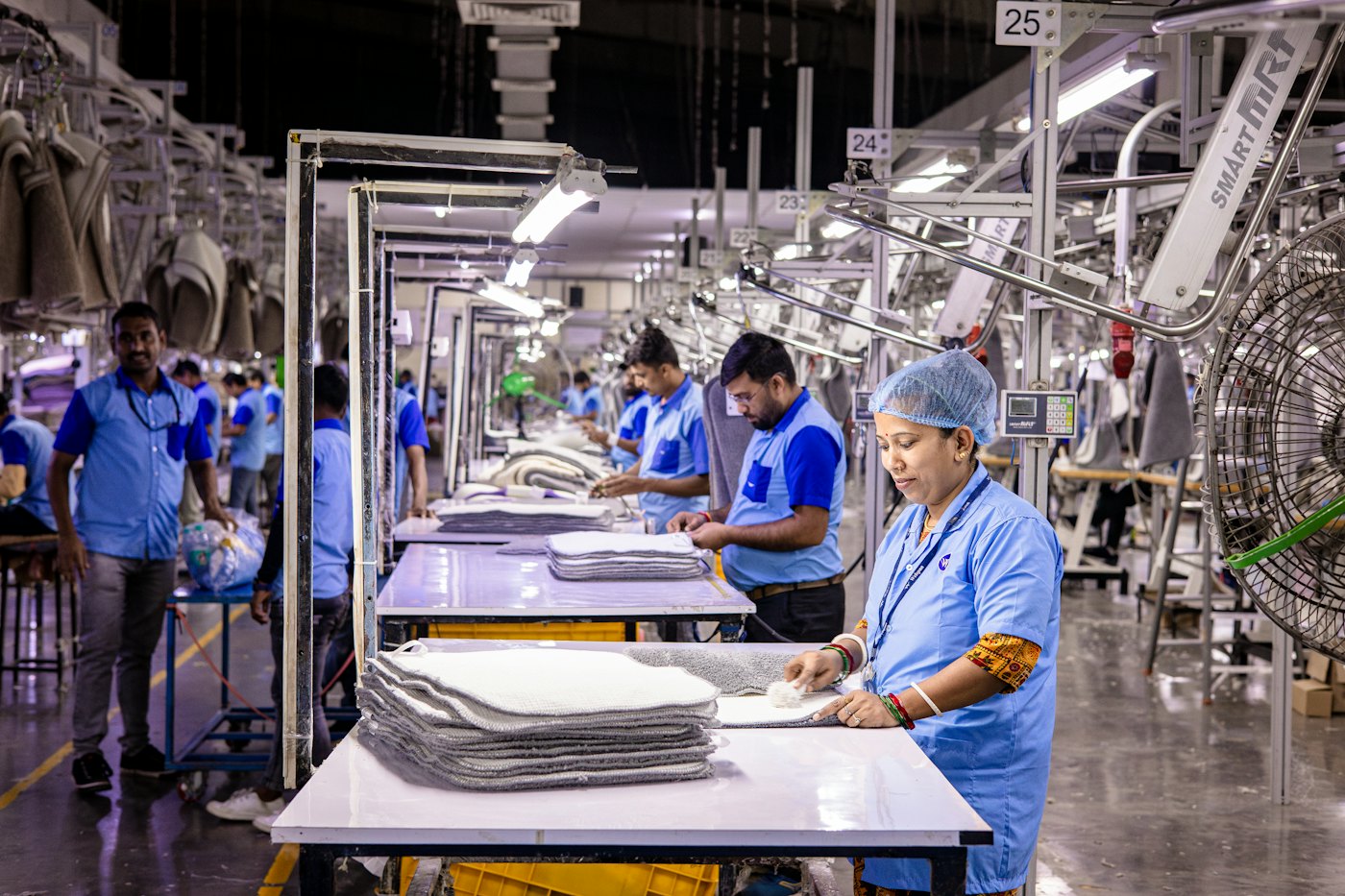 Workers folding towels on a factory floor, with the AI camera checking safety gear and counting stacks.