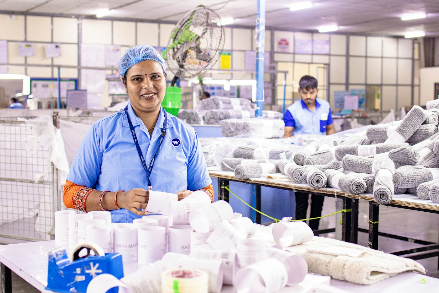 A factory worker smiling at her workstation.