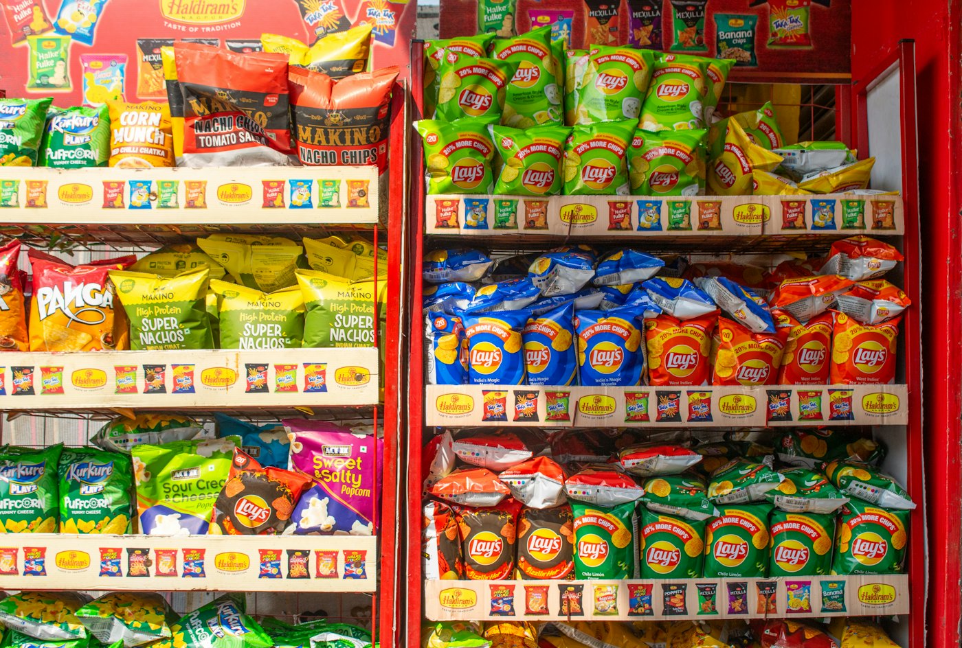 Shop shelves stocked with packets of chips, one row running low.