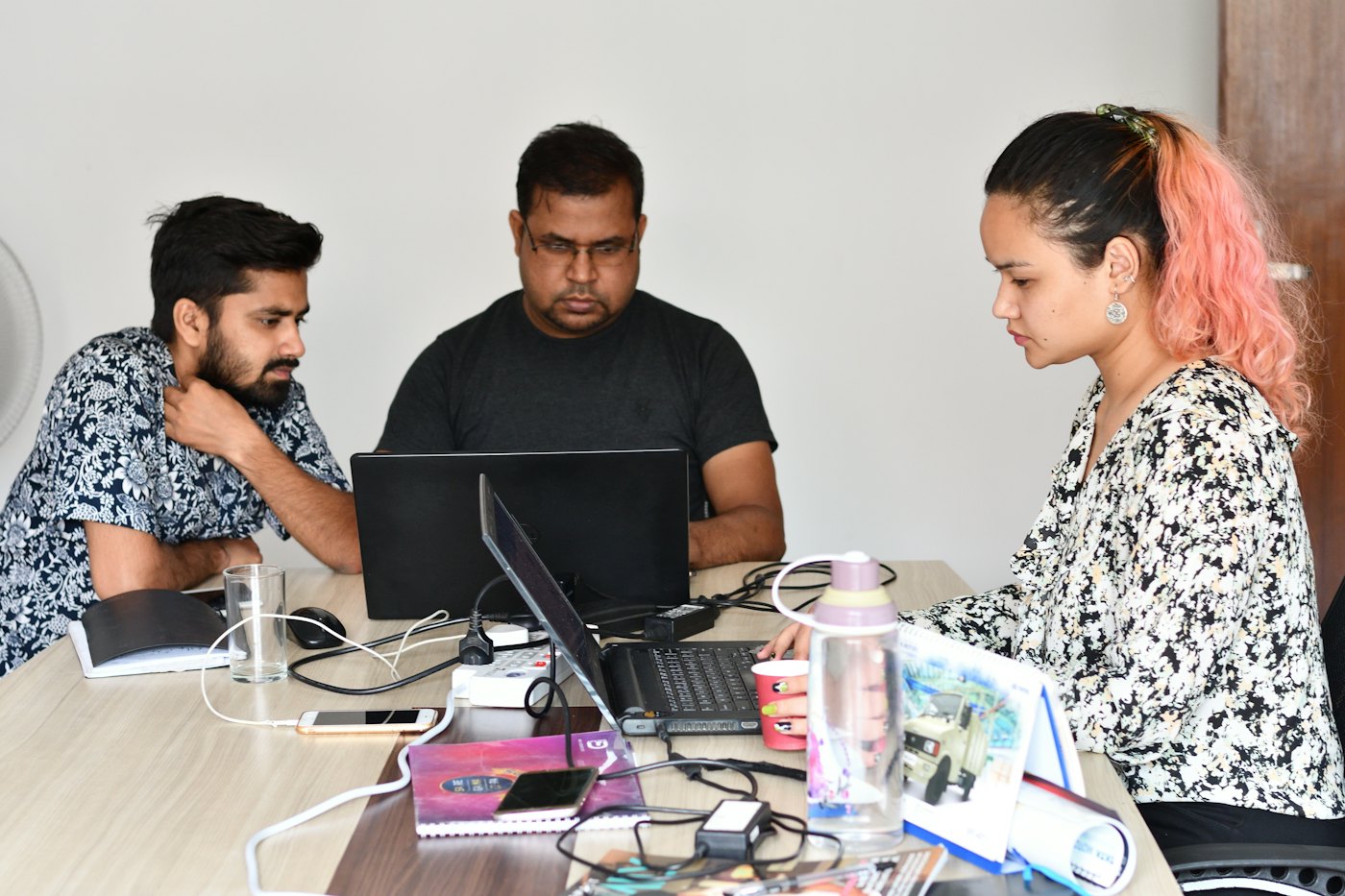 Three colleagues working together on laptops.